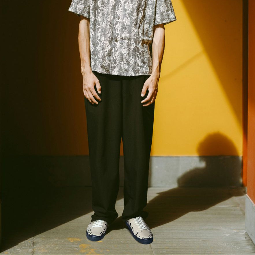 Pair of beige Nappa leather mid-top sneakers with exclusive printed black drops design on model worn with black pants