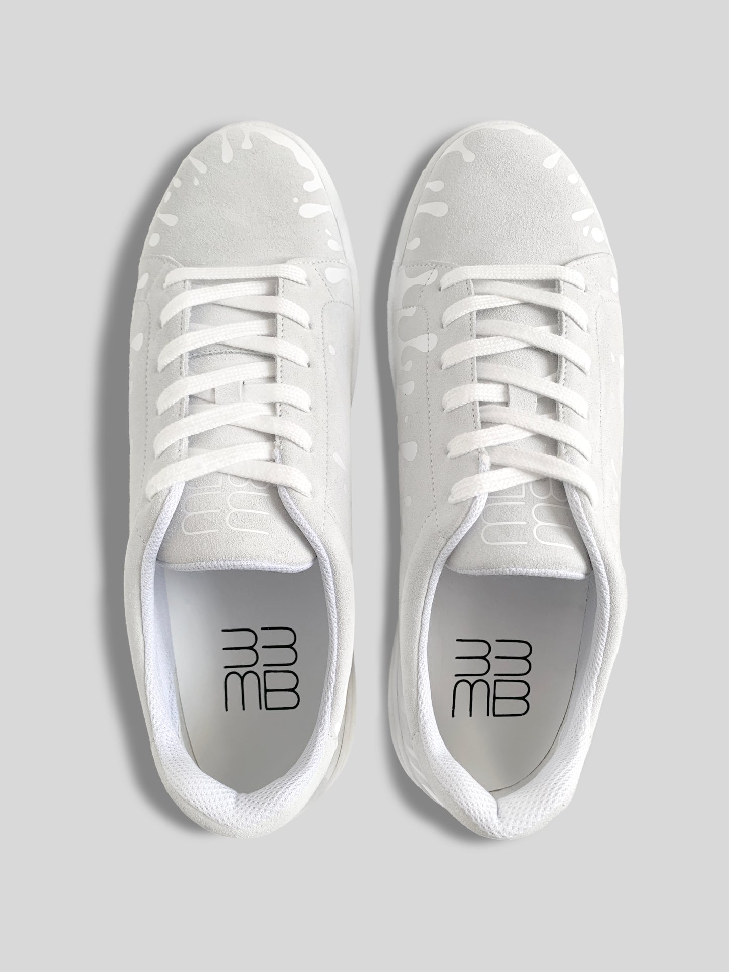 Top view of pair of white suede low-top sneakers with exclusive printed white drops design