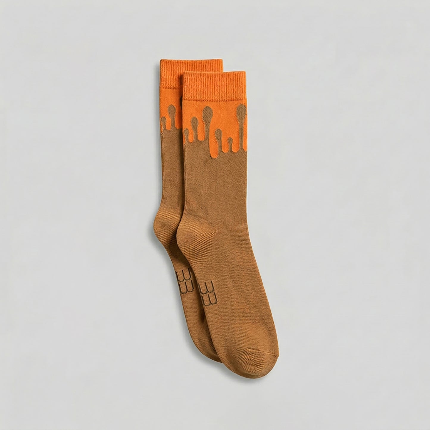 Pair of premium 33MB organic cotton crew socks in camel and orange featuring the Zero Gravity® signature motif of paint droplets flowing upward, symbolizing hope and constant positivity