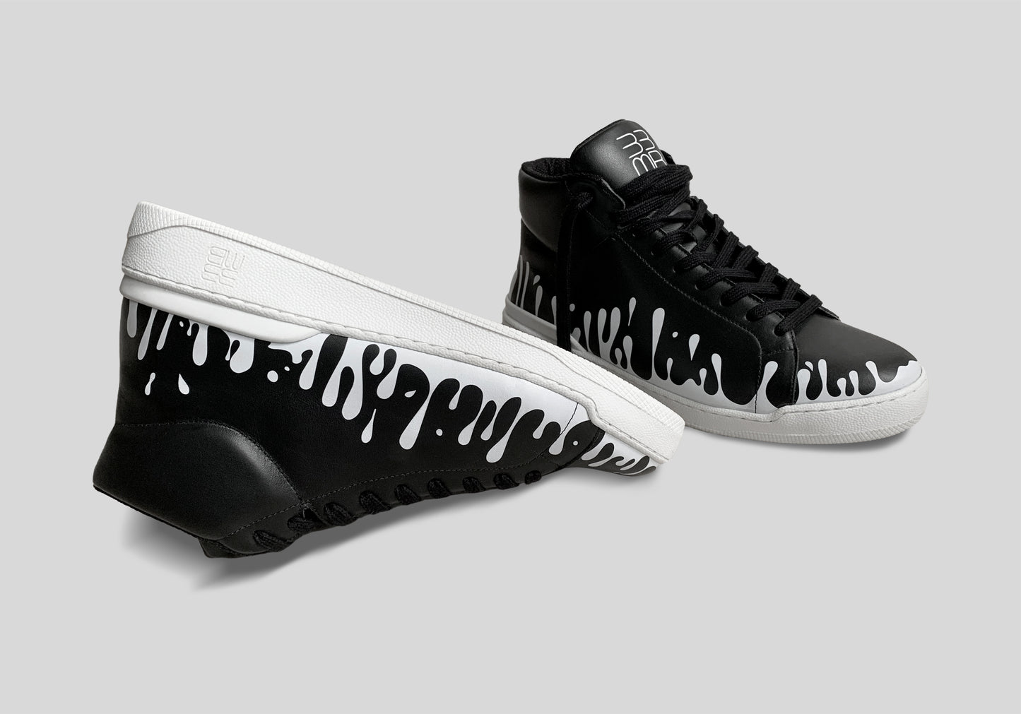 Upside down view of pair of black Nappa leather mid-top sneaker with exclusive printed white drops design and white soles