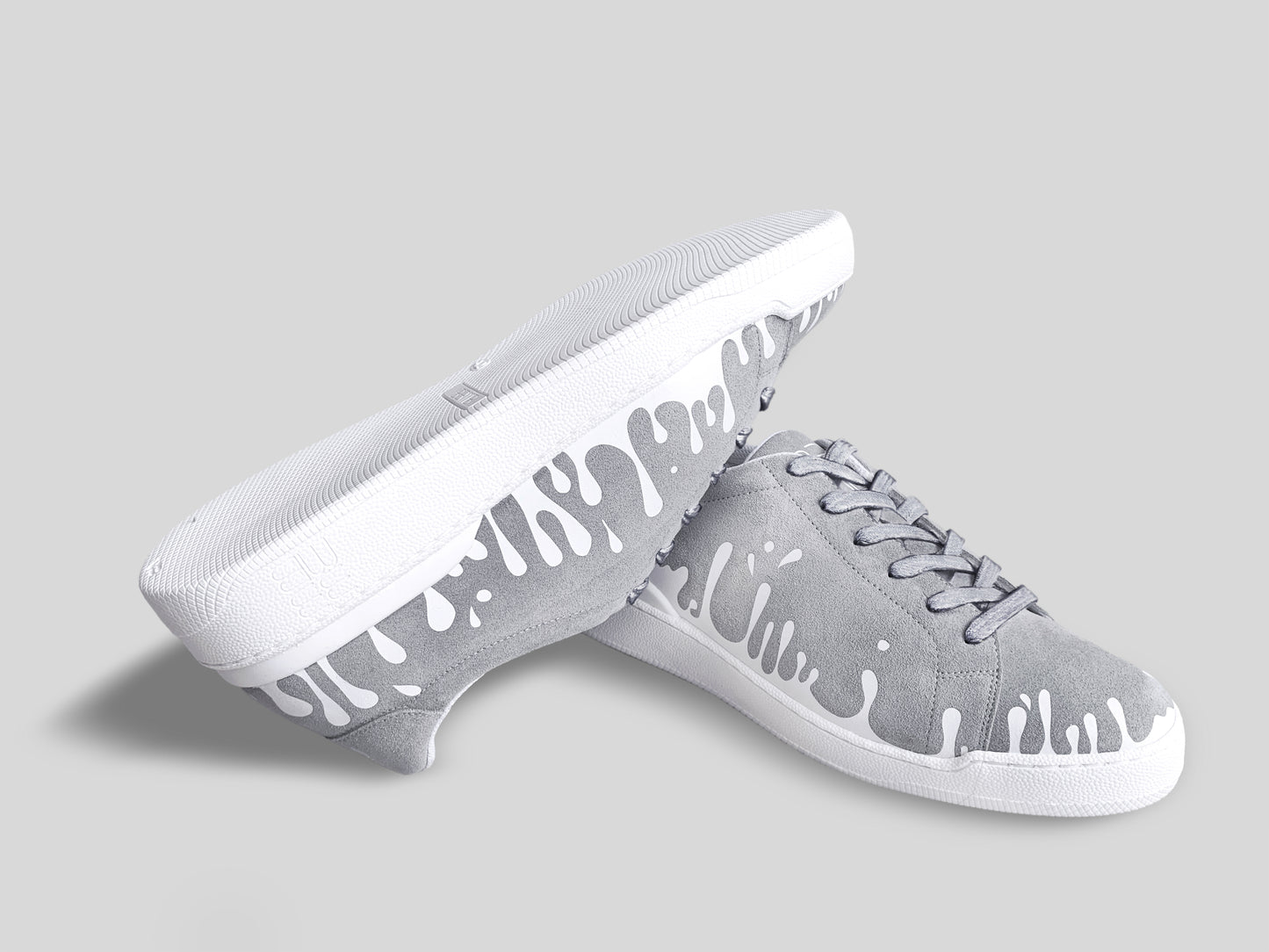 Upside down view of grey suede low-top sneakers with exclusive printed white drops design and white soles
