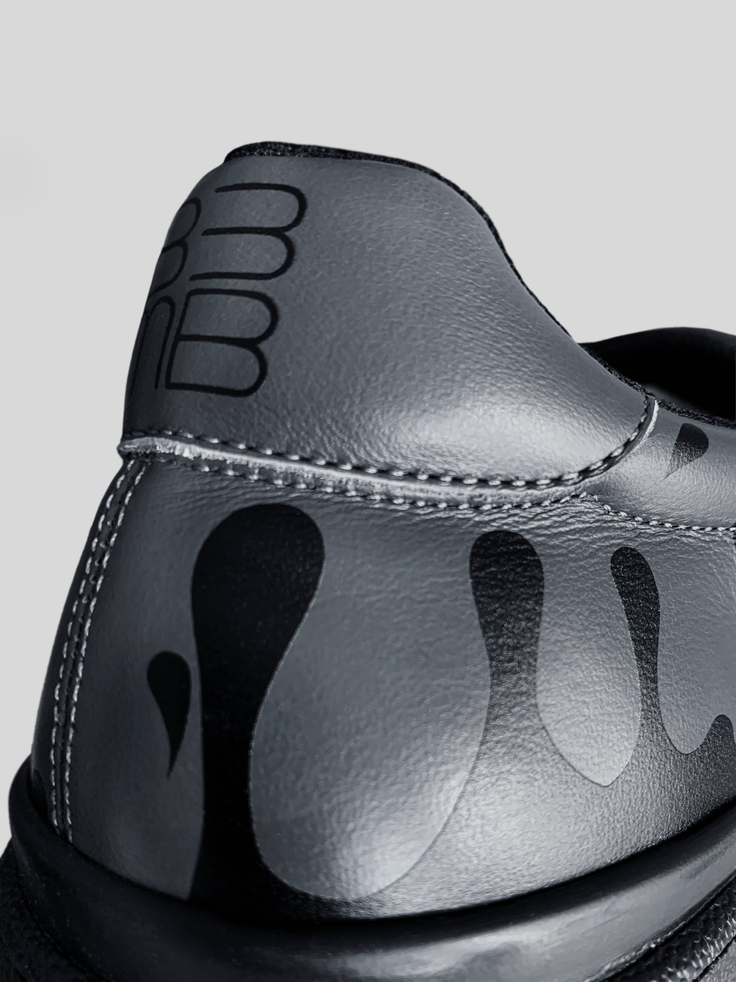 Close-up of Zero Gravity® black upward drops on soft dark grey Italian leather, showcasing the unique 33MB artistic signature and hope symbolism.