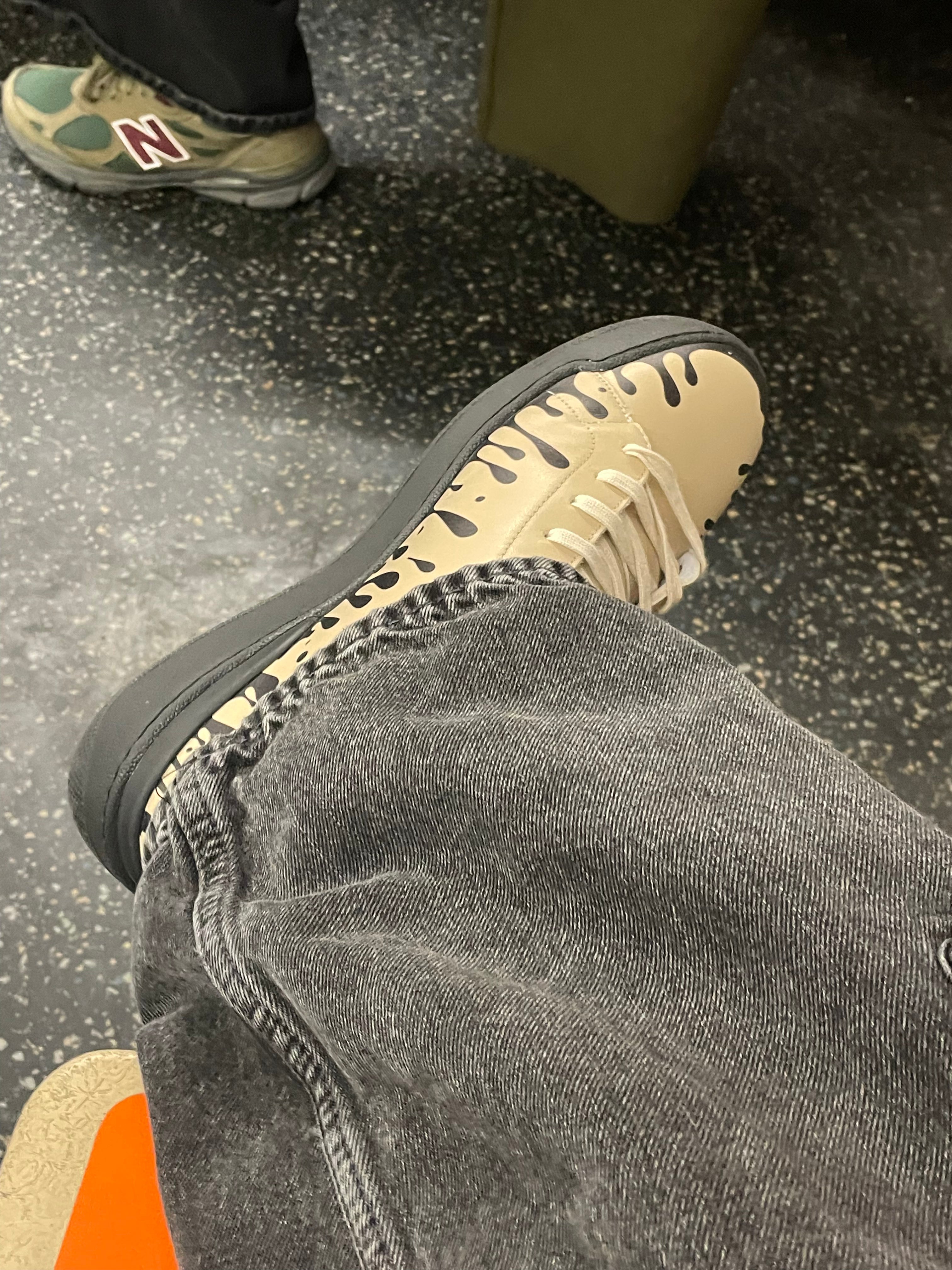 Beige Nappa leather mid-top sneaker with exclusive printed black drops design and black sole worn with grey jeans