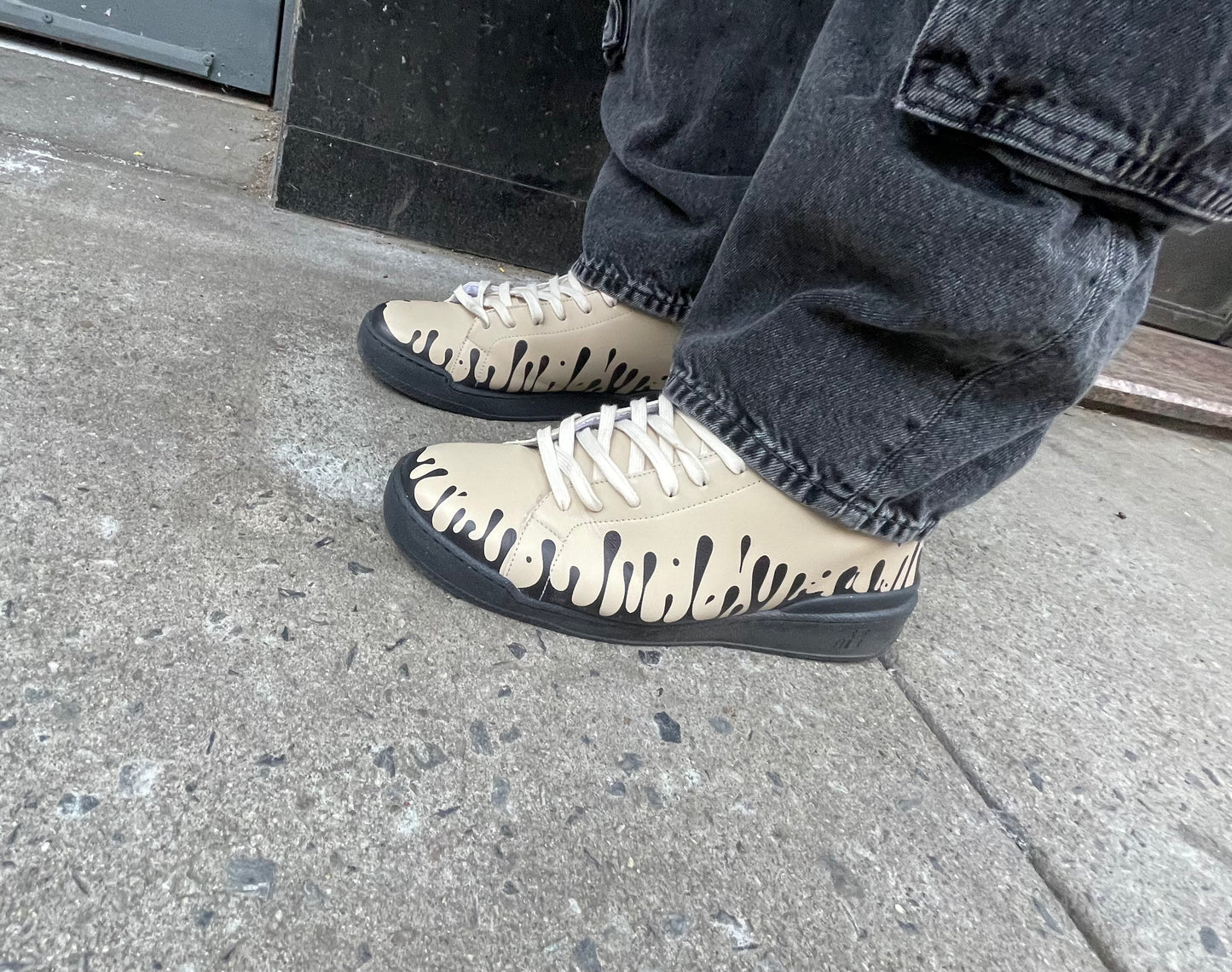 Beige leather sneakers with black design worn with jeans