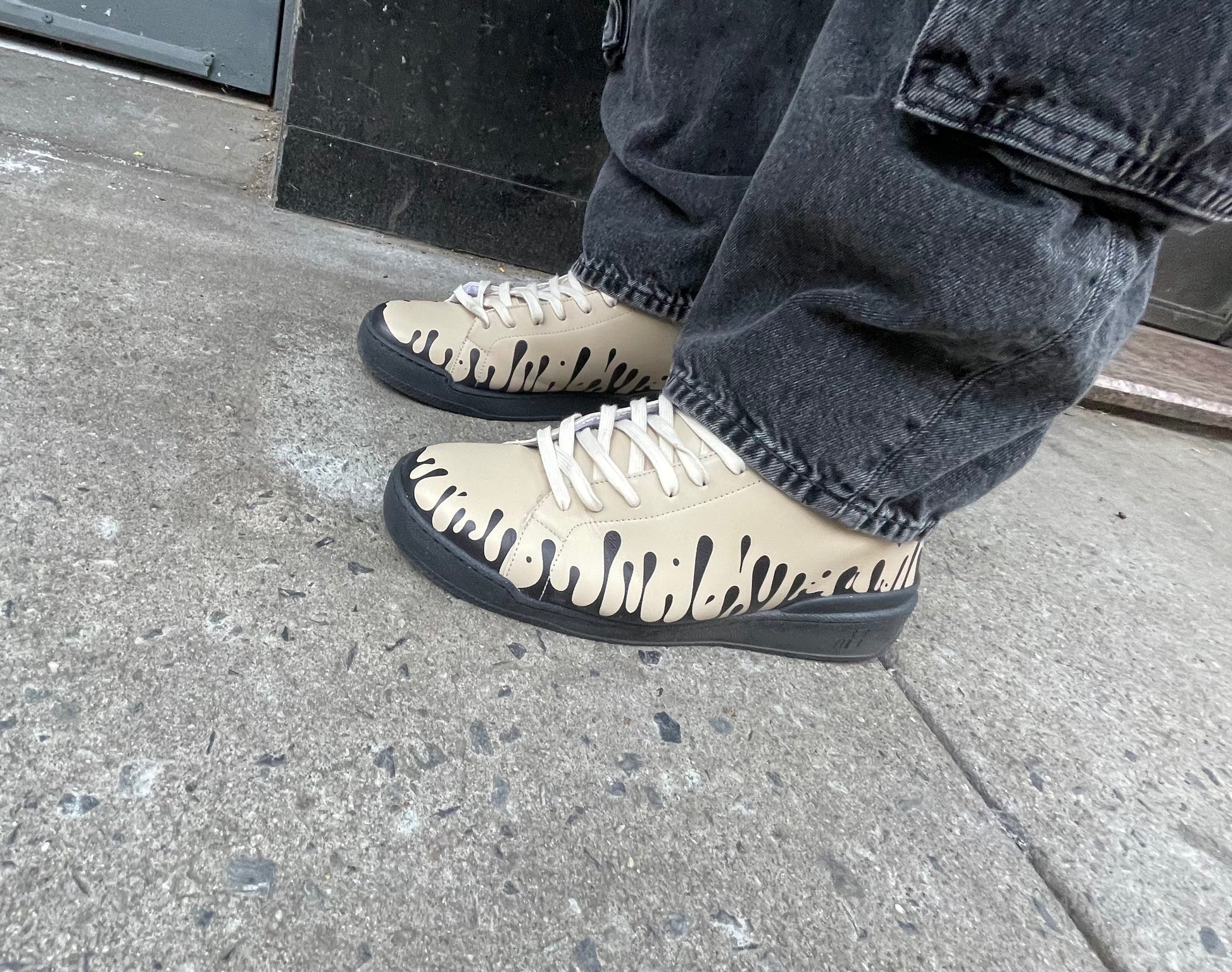 Beige leather sneakers with black design worn with jeans
