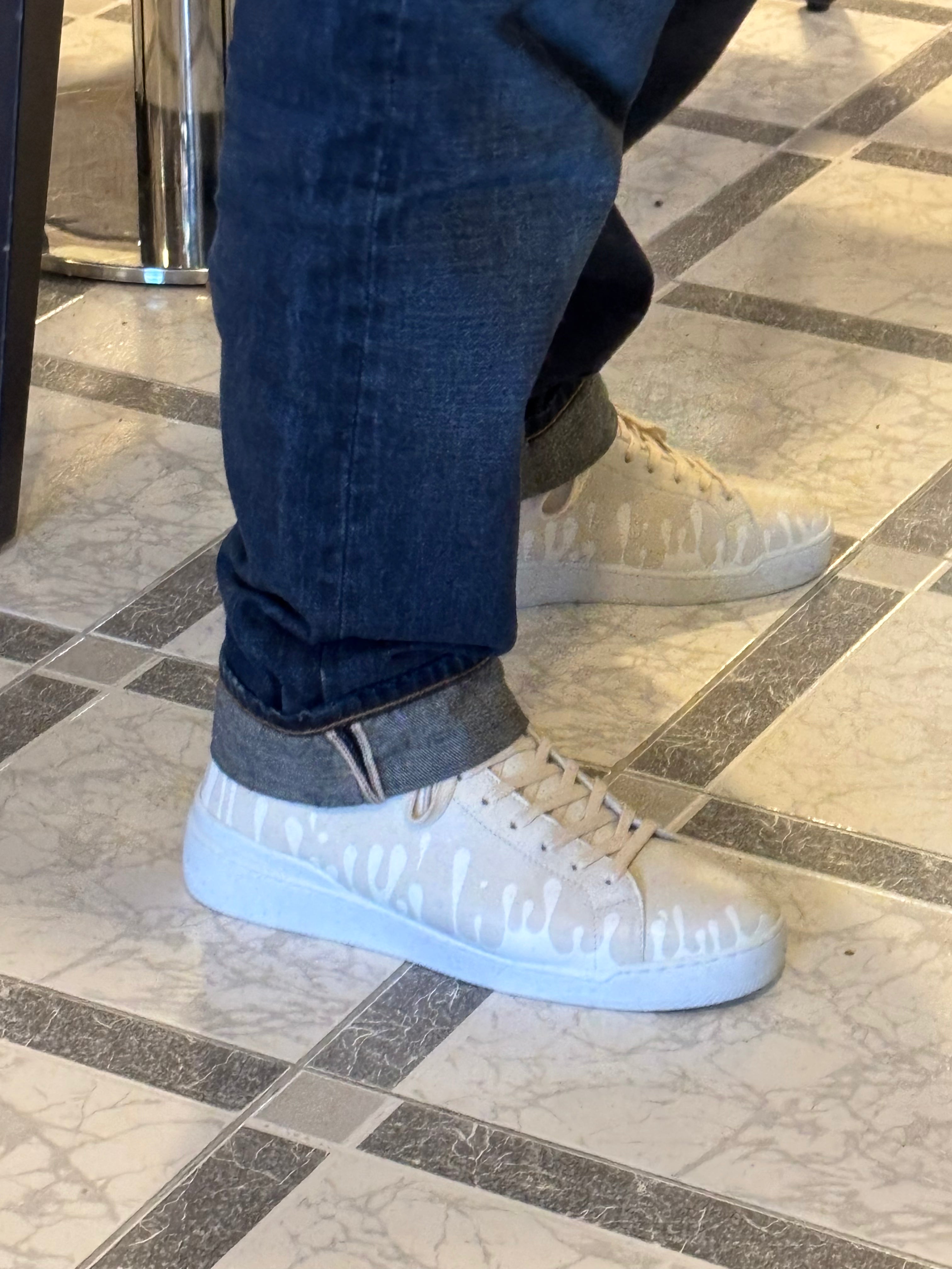 Pair of cream color Nappa leather mid-top sneakers with exclusive printed white drops design and white soles worn with blue jeans