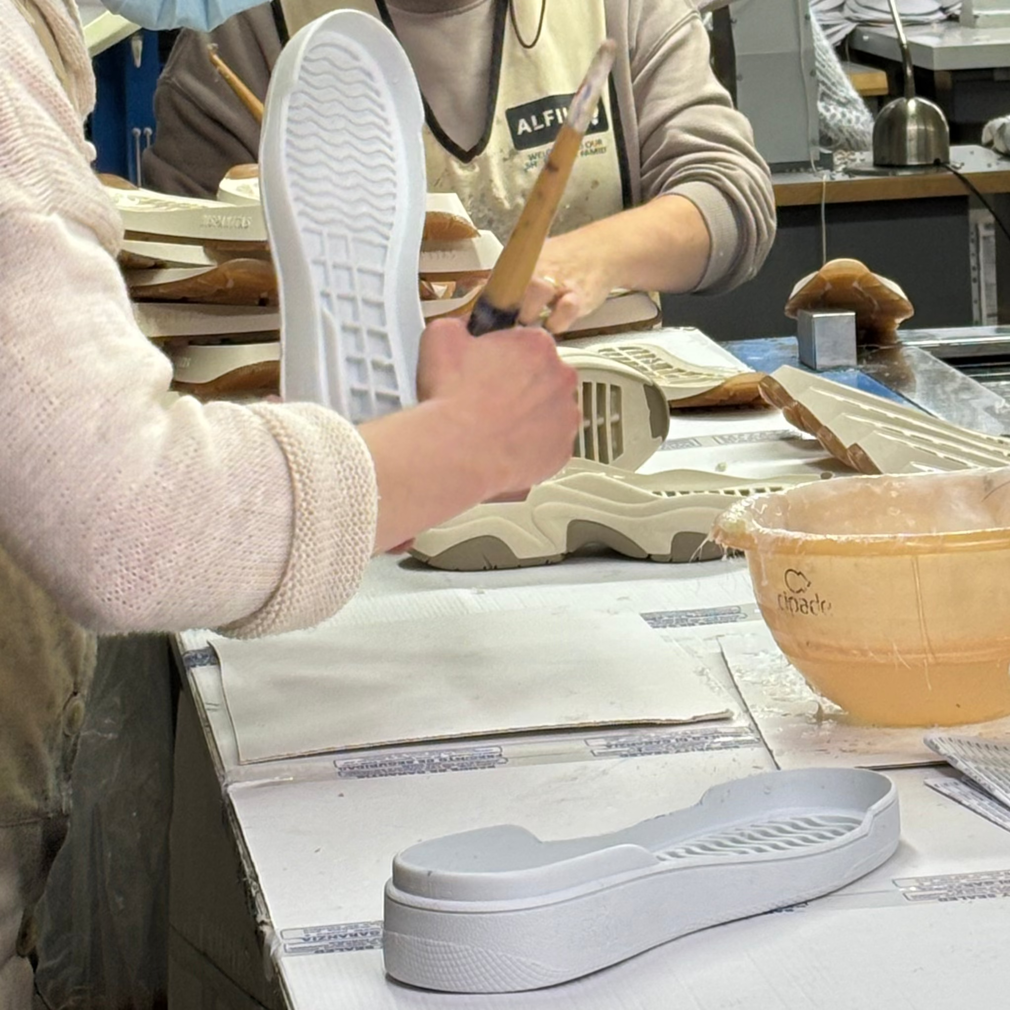 Craftman applying glue to sneakers outsoles