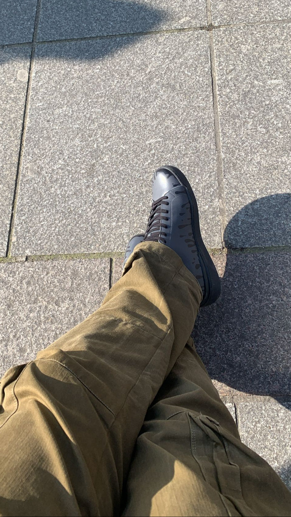 Dark grey Chrome-free Nappa leather mid-top sneaker with exclusive printed black drops design and black sole worn with khaki pants