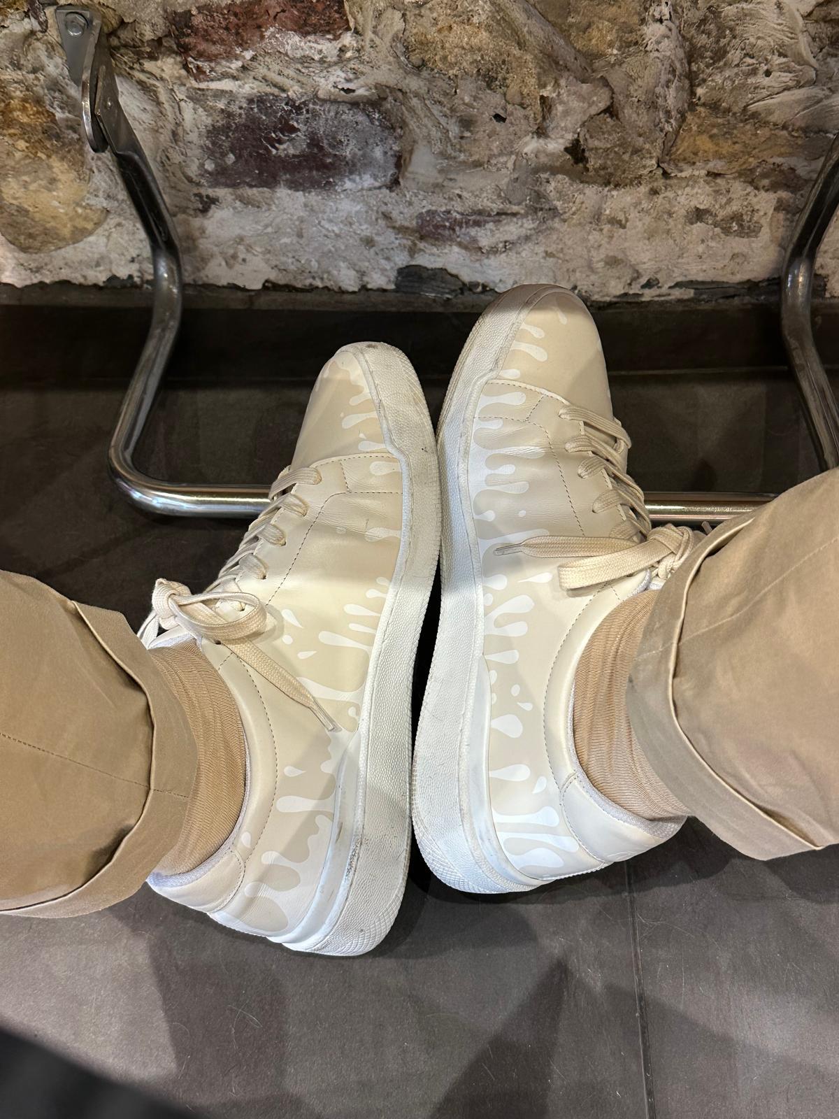 Cream color Nappa leather low-top sneaker with exclusive printed white drops design and white soles worn with khakis