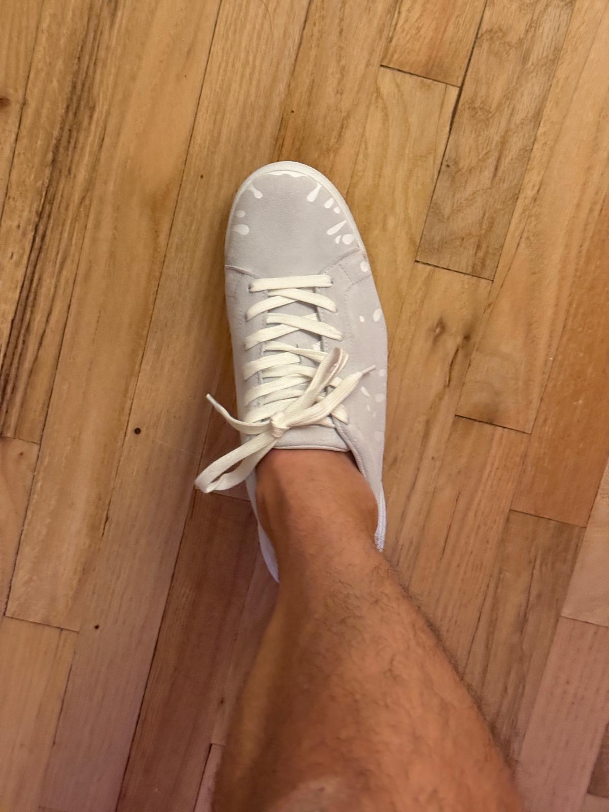 White suede low-top sneaker with exclusive printed white drops design and white sole on wooden floor