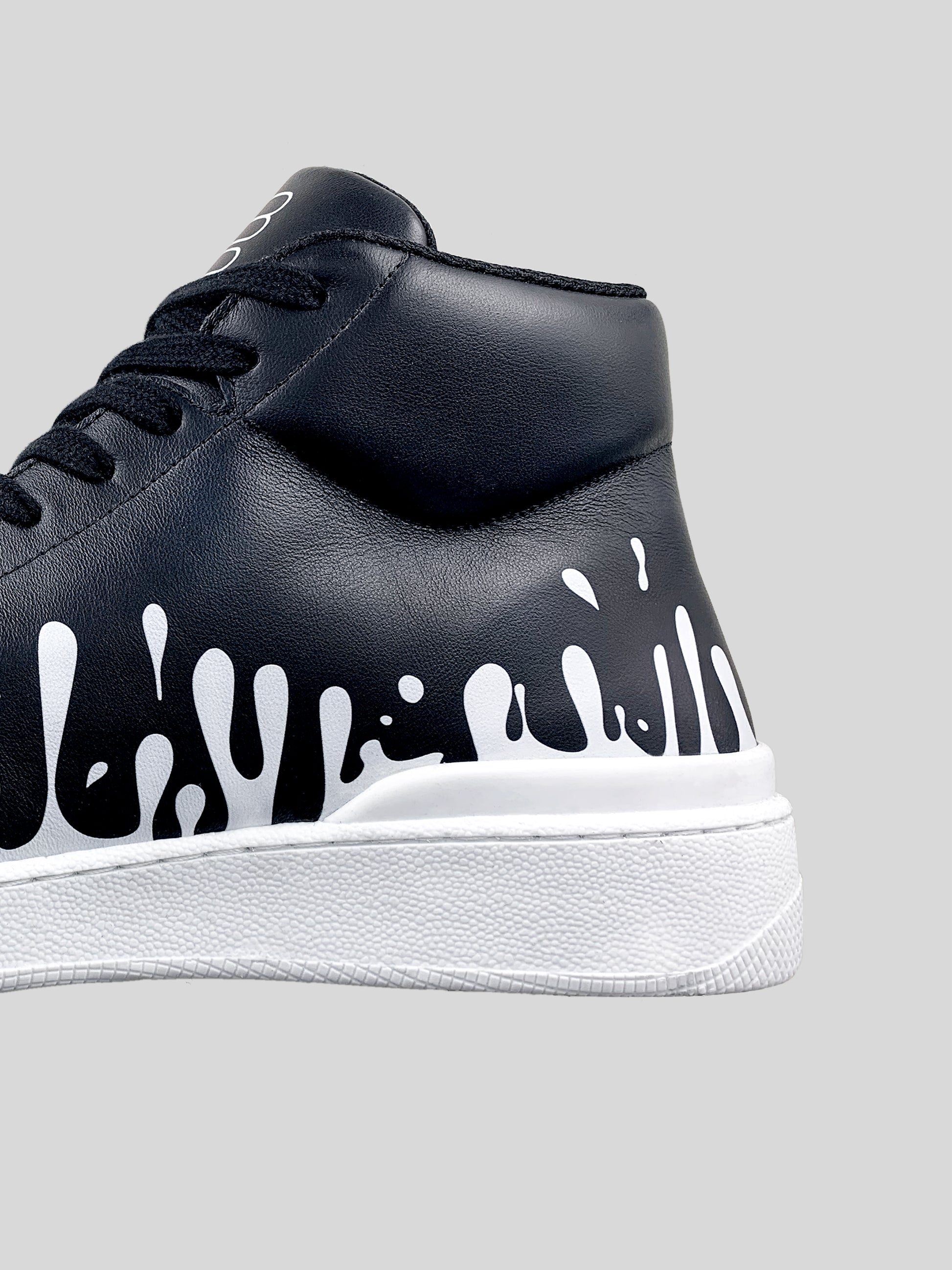 Back side focus of black Nappa leather mid-top sneaker with exclusive printed white drops design and white sole