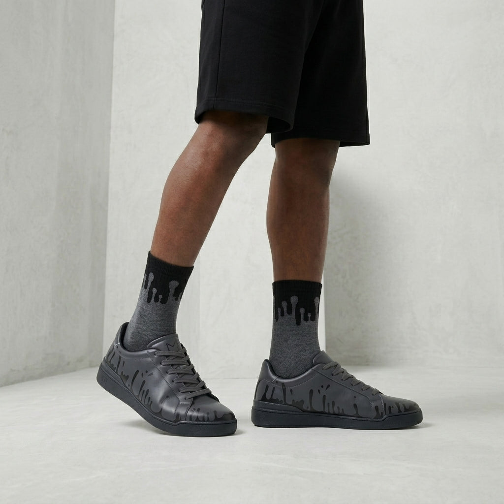 Model standing, wearing the Eclipse Zero Gravity© socks in a dark grey and black palette, styled with urban Nighty low 33MB sneakers and shorts.