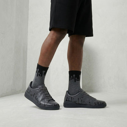 Model standing, wearing the Eclipse Zero Gravity© socks in a dark grey and black palette, styled with urban Nighty low 33MB sneakers and shorts.