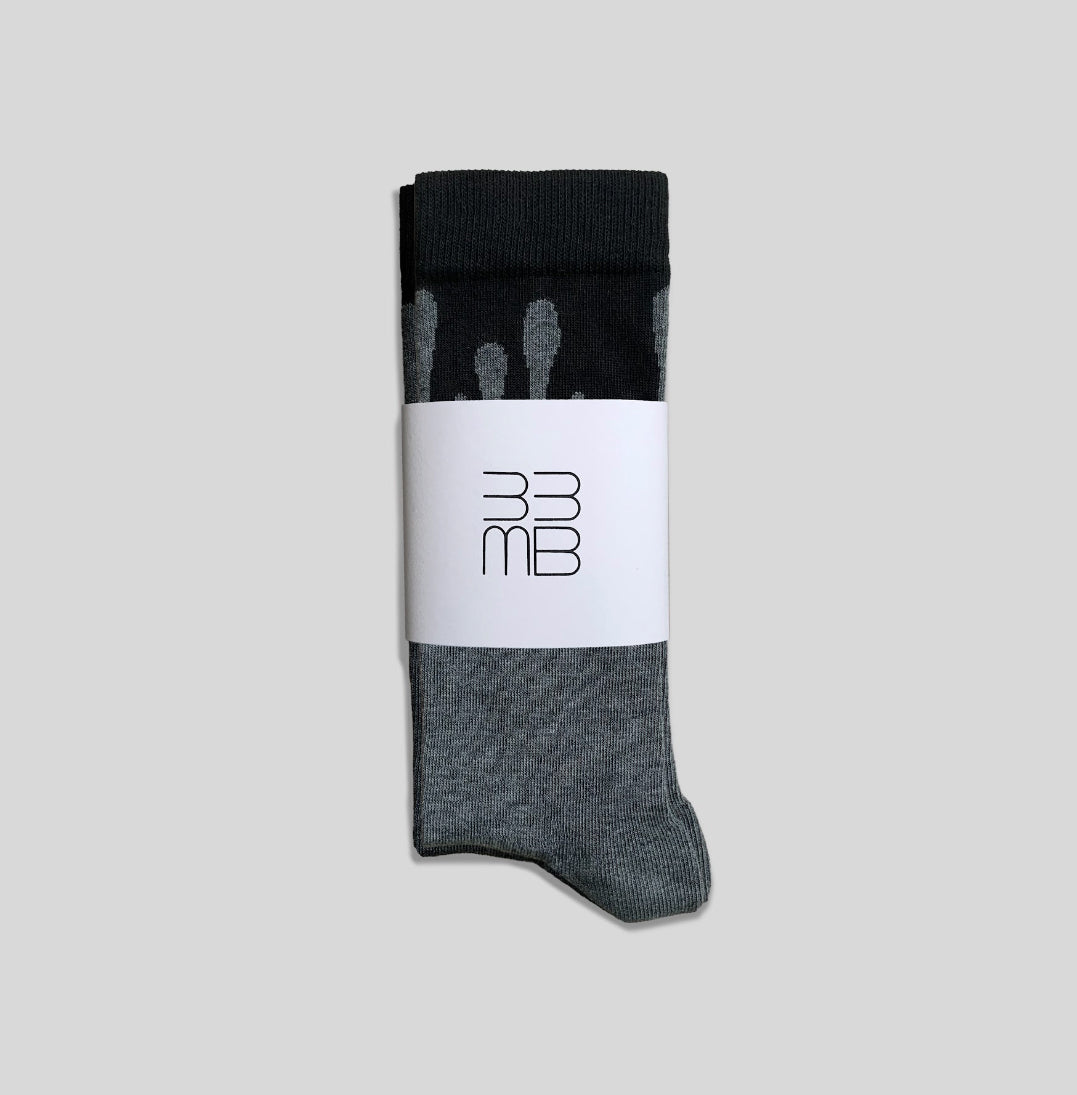 Folded 33MB premium organic cotton crew socks featuring a white brand band with the 33MB logo and the Zero Gravity design of grey paint droplets flowing upward to symbolize hope and constant positivity.