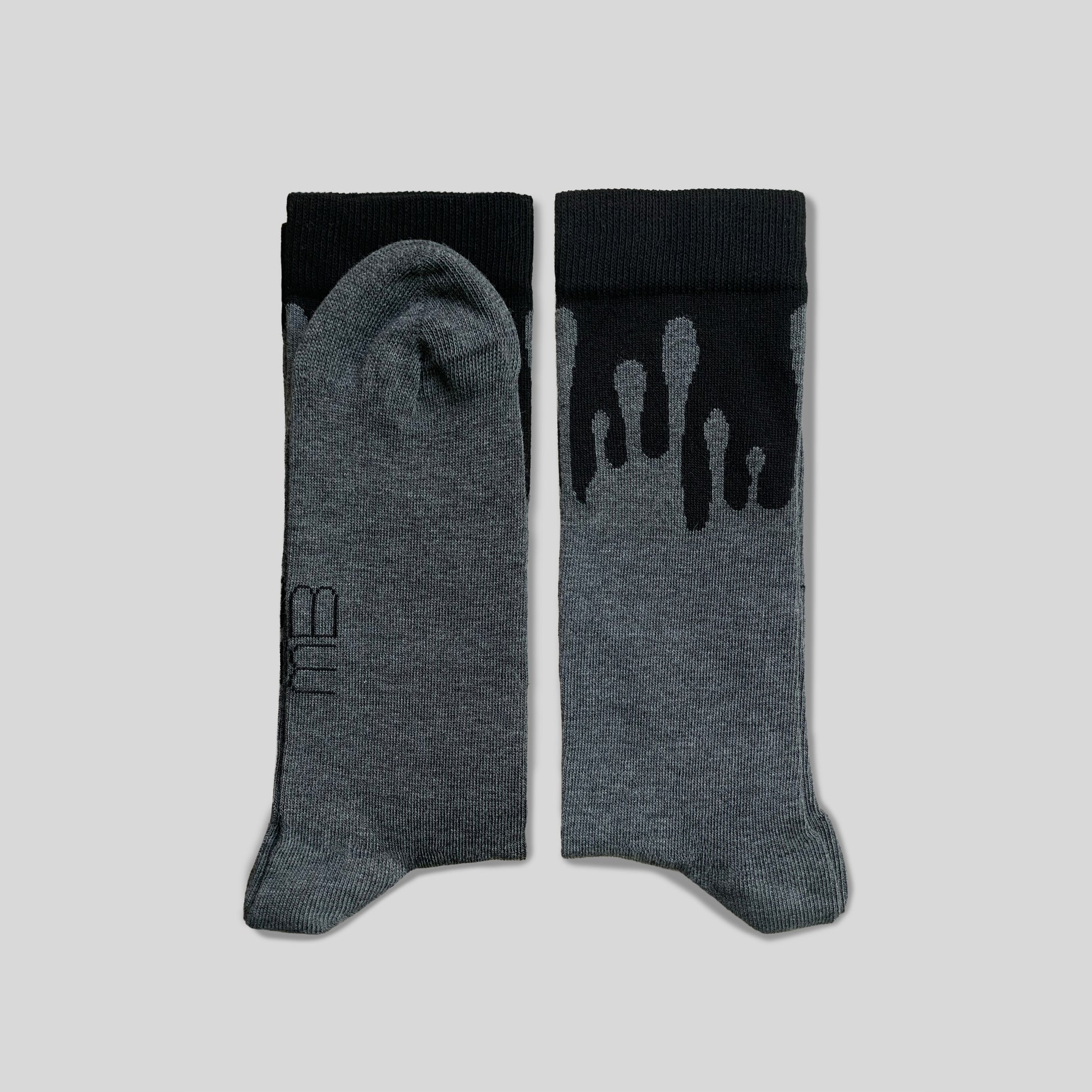 Folded 33MB brand organic cotton crew socks. The "Zero Gravity" pattern shows grey paint splatters moving vertically toward the black cuff, symbolizing upward momentum and positivity.
