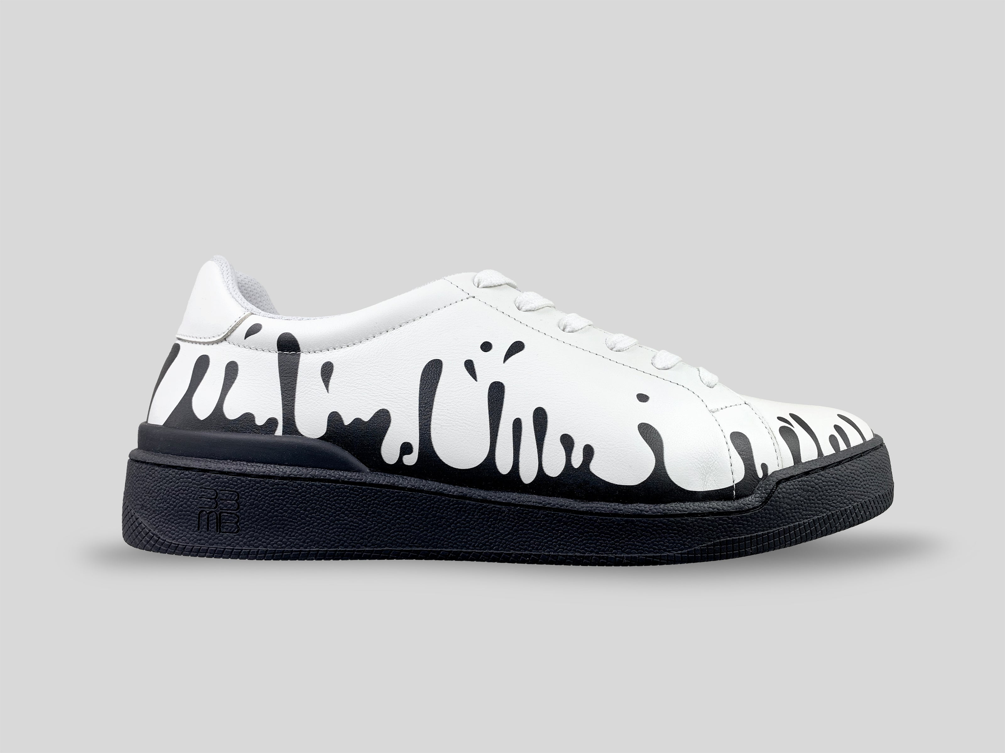 Side profile of 33MB Yang low-top sneakers in white leather, featuring high-contrast black Zero Gravity® paint drops traveling upward from the sole.
