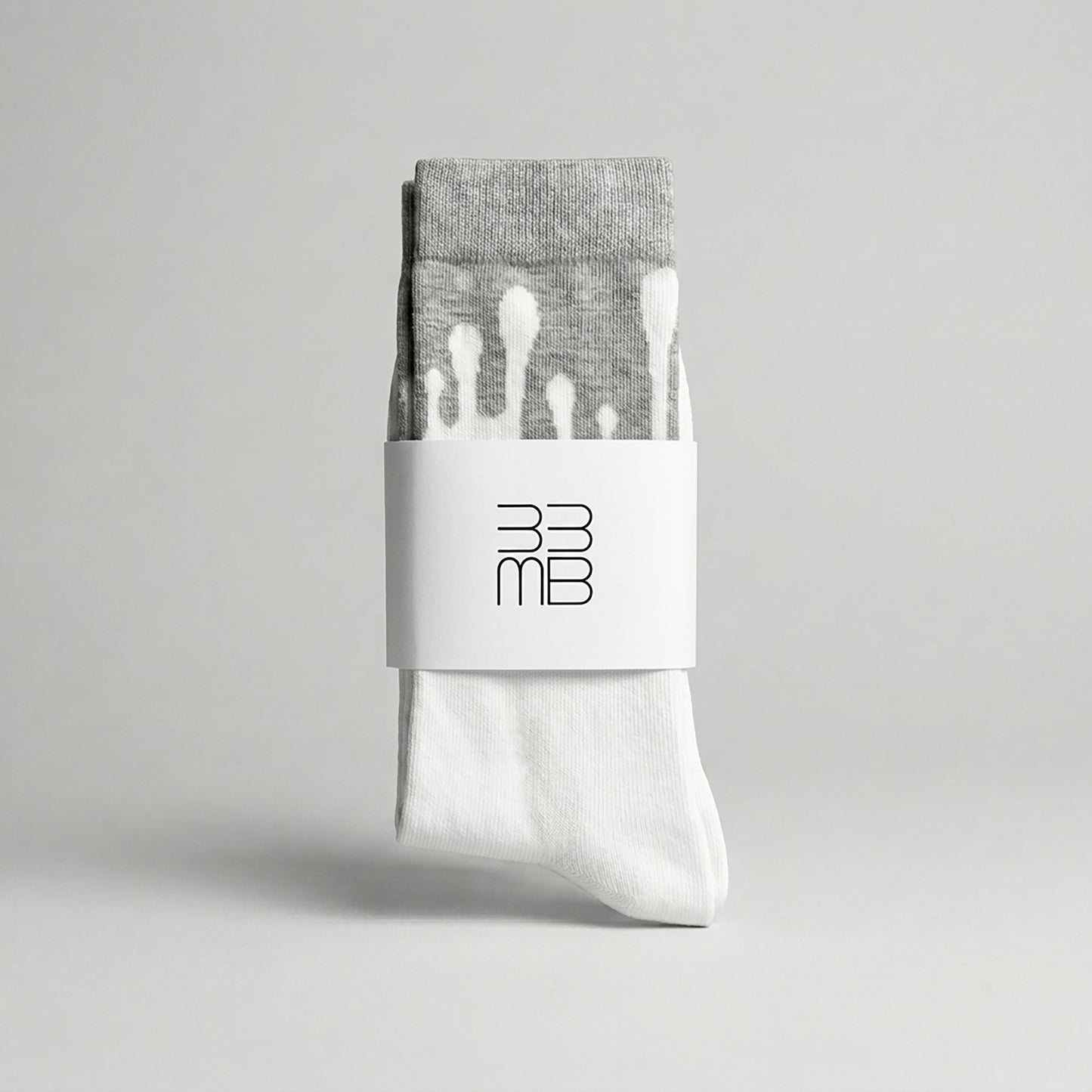 Folded 33MB premium organic cotton crew socks featuring a white brand band with the 33MB logo and the Zero Gravity design of white paint droplets flowing upward toward the grey cuff to symbolize hope and constant positivity.