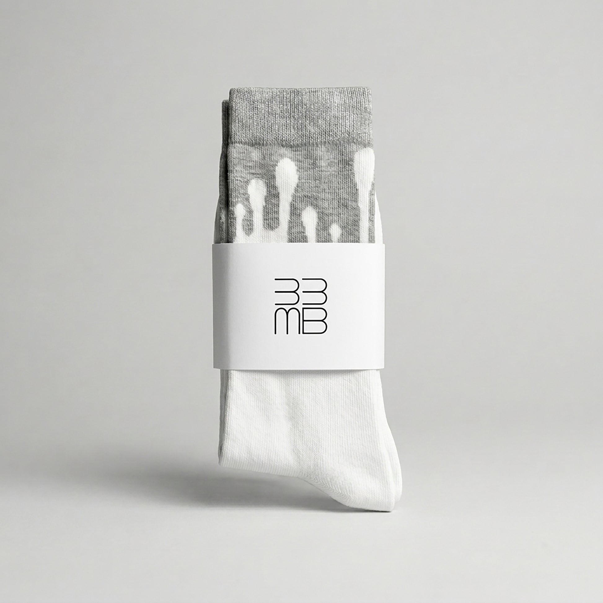 Folded 33MB premium organic cotton crew socks featuring a white brand band with the 33MB logo and the Zero Gravity design of white paint droplets flowing upward toward the grey cuff to symbolize hope and constant positivity.
