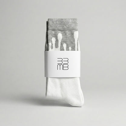 Folded 33MB premium organic cotton crew socks featuring a white brand band with the 33MB logo and the Zero Gravity design of white paint droplets flowing upward toward the grey cuff to symbolize hope and constant positivity.