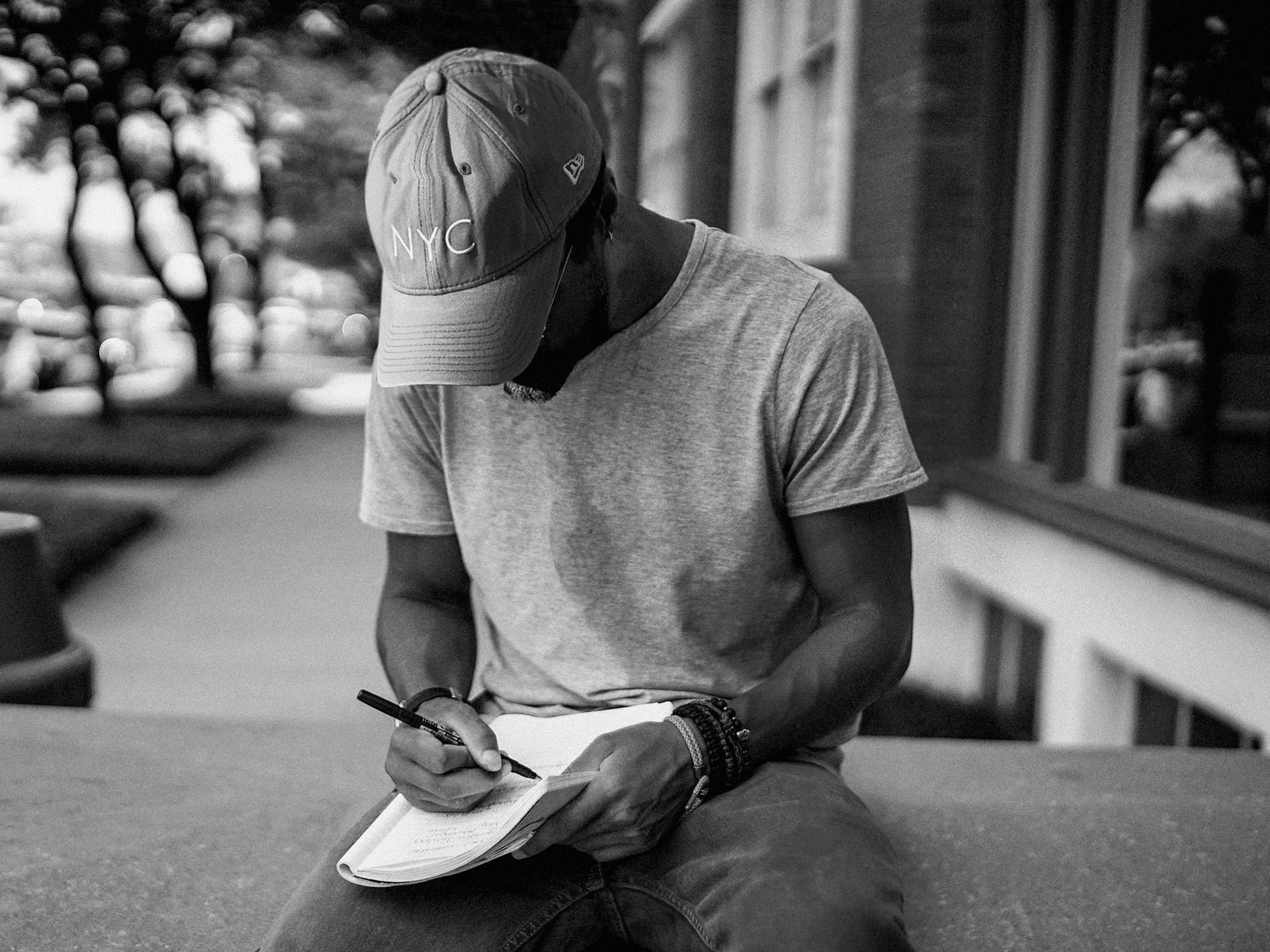Miguel Berthelot 33MB founder wearing a cap with 'NYC' drawing in a notebook outdoors.