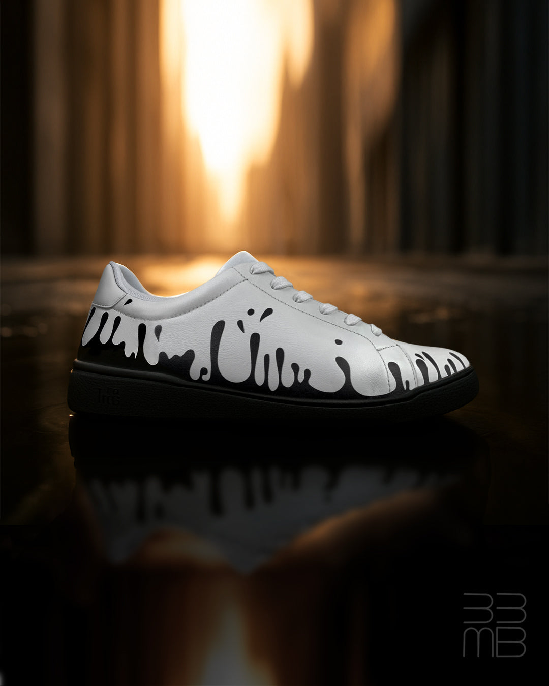 White leather sneaker with black drops design on a reflective surface with blurred background
