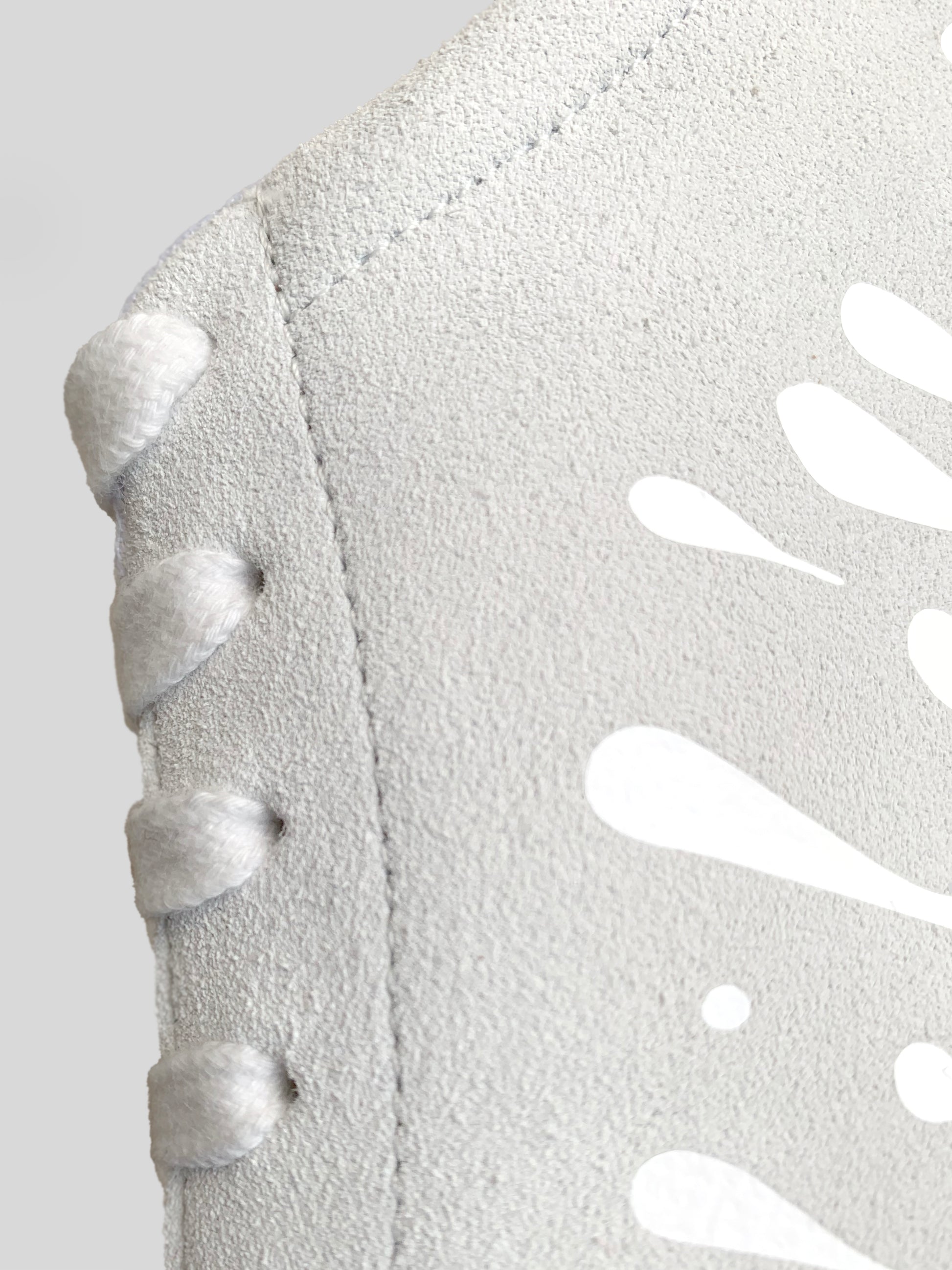 Side focus of white suede low-top sneaker with exclusive printed white drops design